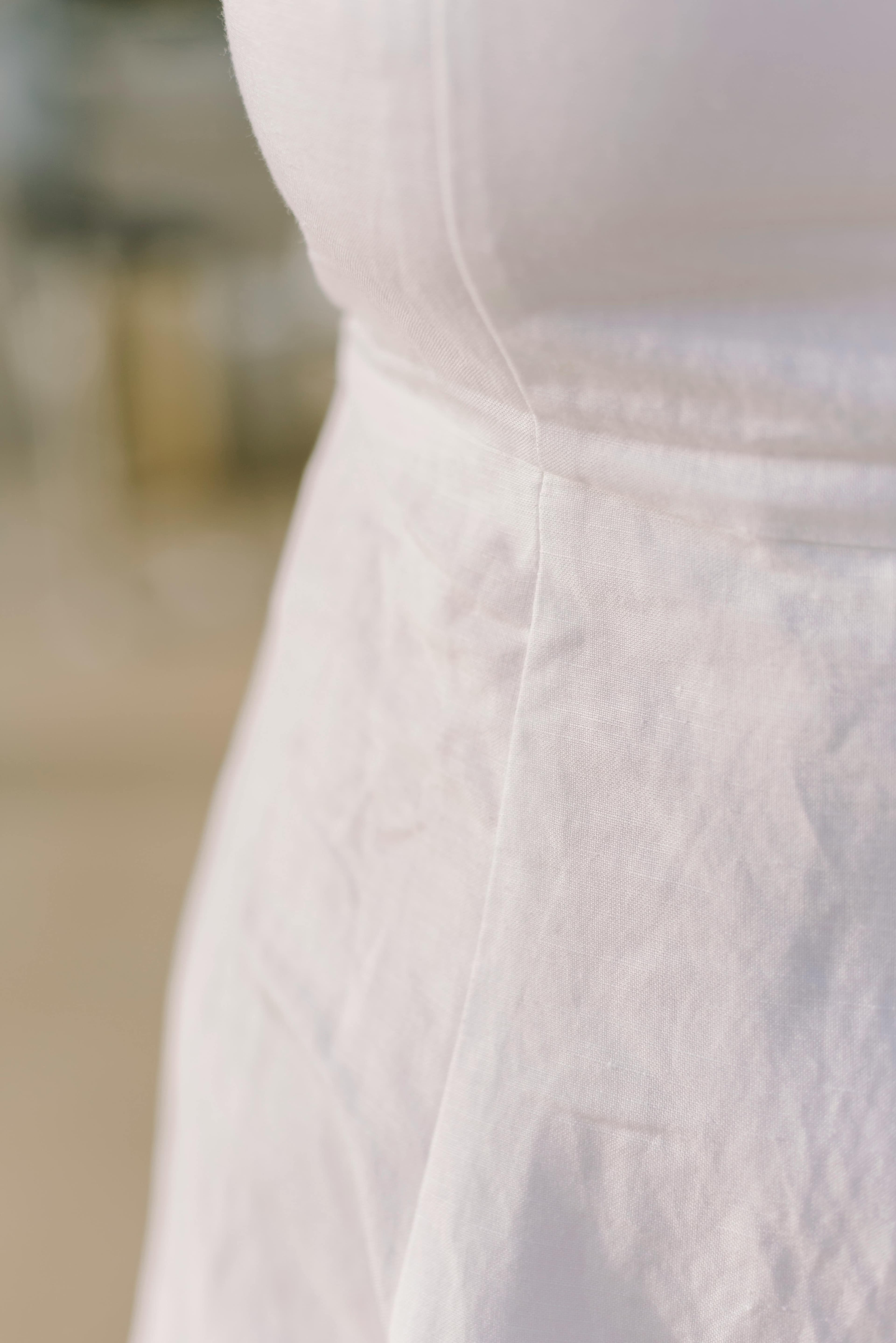 Close-up of undyed cotton fabric showing hand-stitched detail.