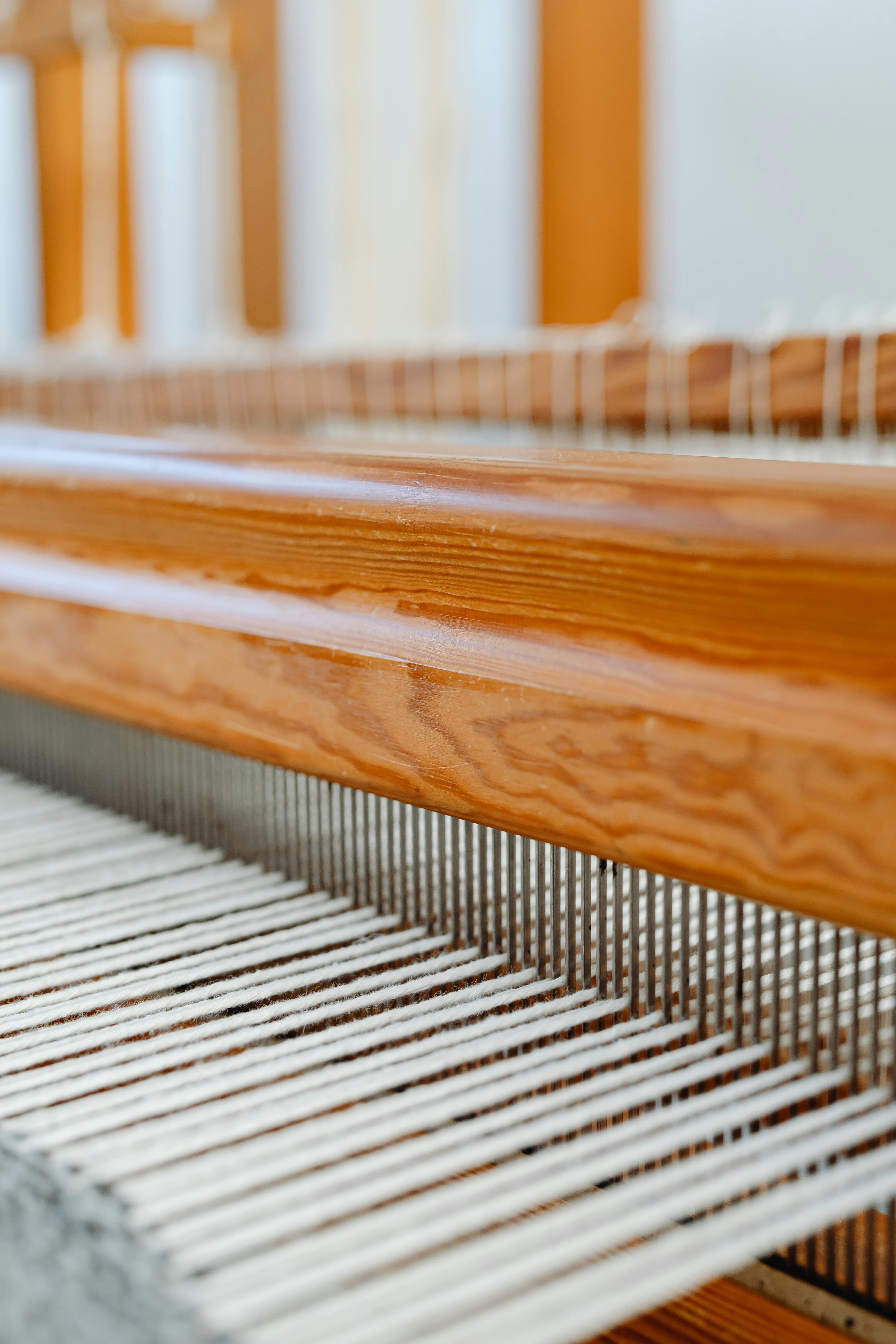 A detail of the wooden loom at the Tangier workshop — white threads under warm light.